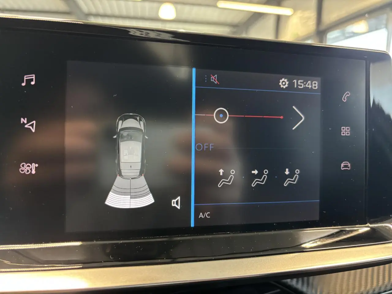 Écran tactile intérieur de la Peugeot 208 blanc, affichant l'aide au stationnement et les réglages de climatisation.