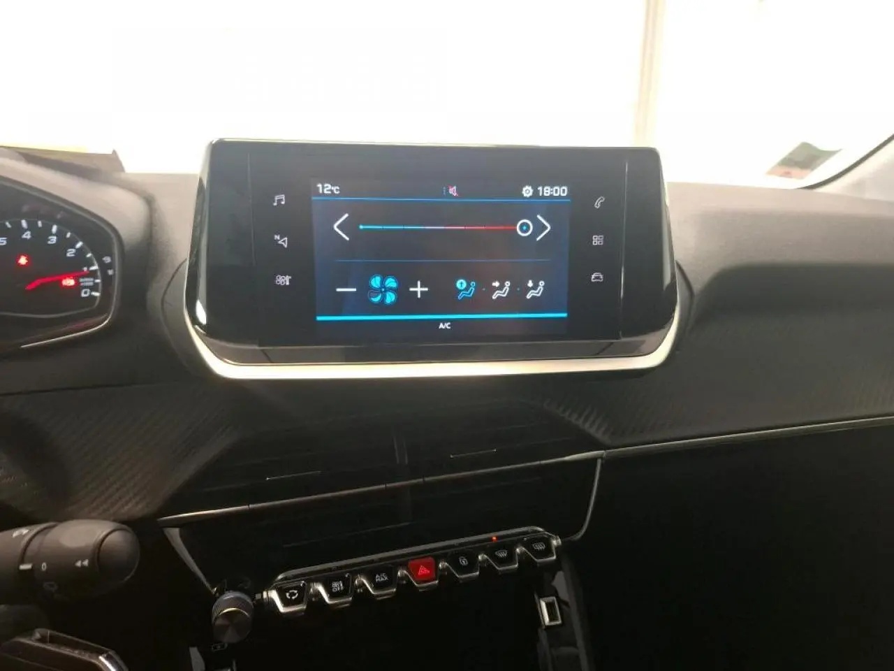 Vue rapprochée du tableau de bord de la Peugeot 208 blanche, avec écran tactile central et commandes piano noires.