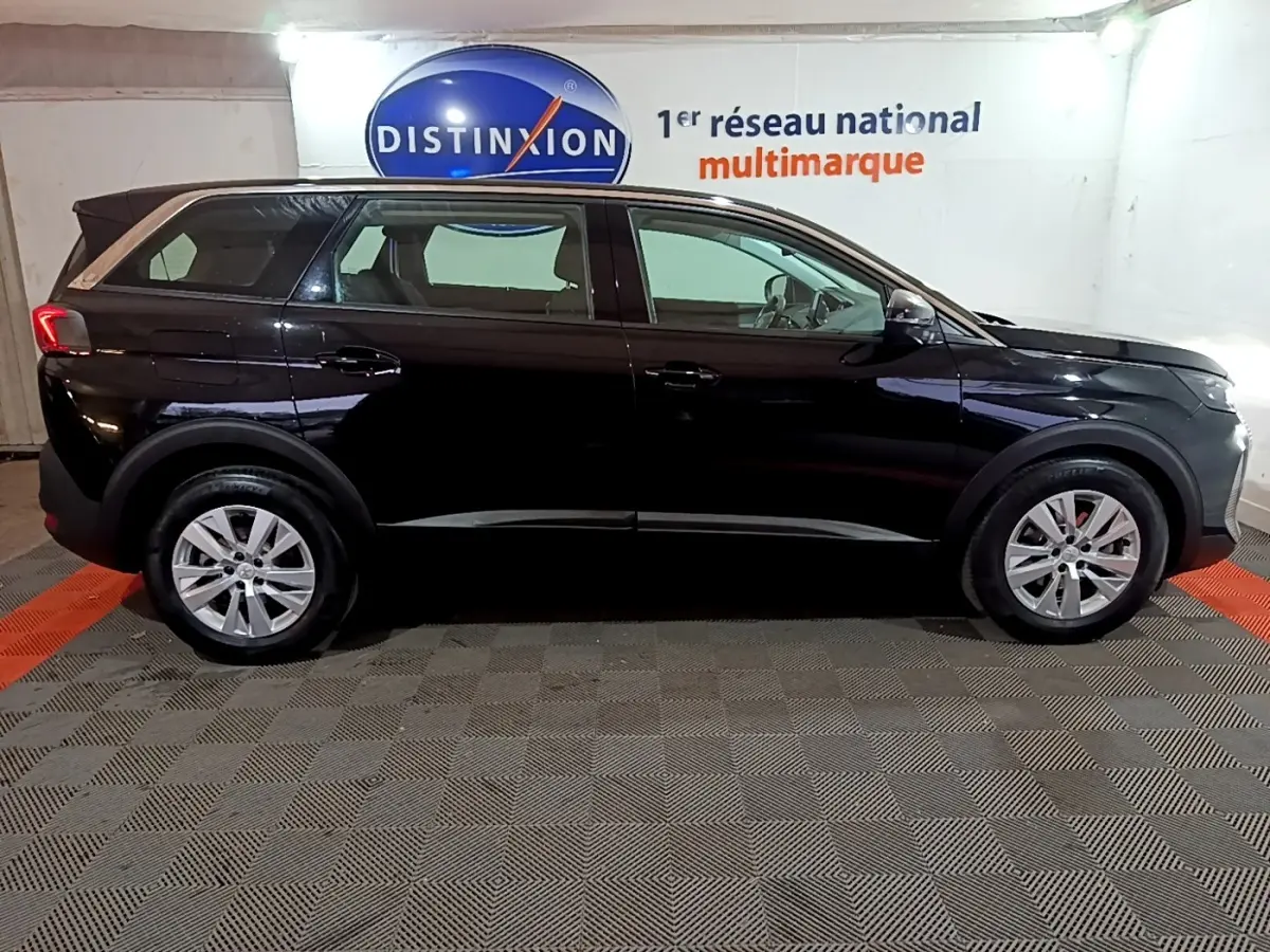 Peugeot 5008 noir vue de profil côté gauche, avec jantes alliage et feux arrière LED visibles en intérieur showroom.