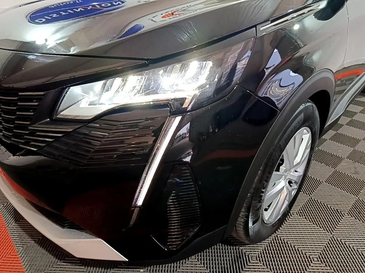 Gros plan sur l'avant droit noir du Peugeot 5008 2021 avec phares LED allumés et jante argentée visible.