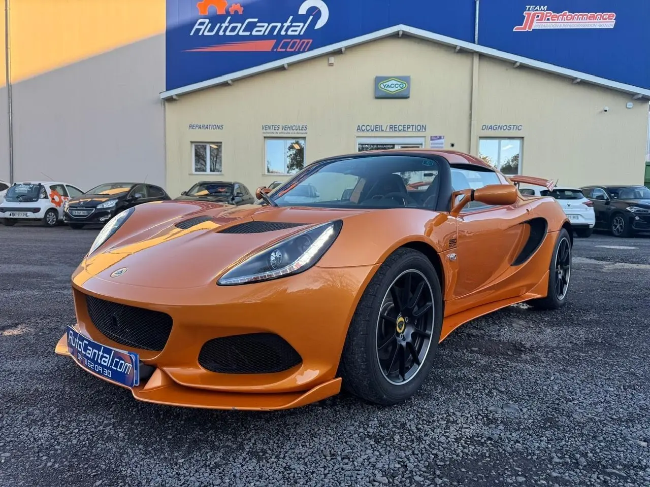 Lotus Elise 3 Cup 250 orange vue 3/4 avant droit, jantes noires satinées et phares LED intégrés visibles.