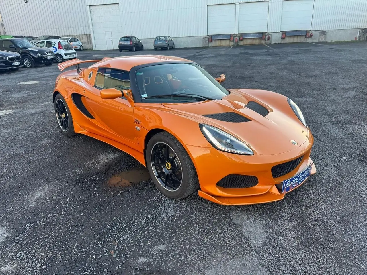Lotus Elise 3 Cup 250 orange vue 3/4 avant droit, jantes noires satinées et prises d'air noires sur capot.