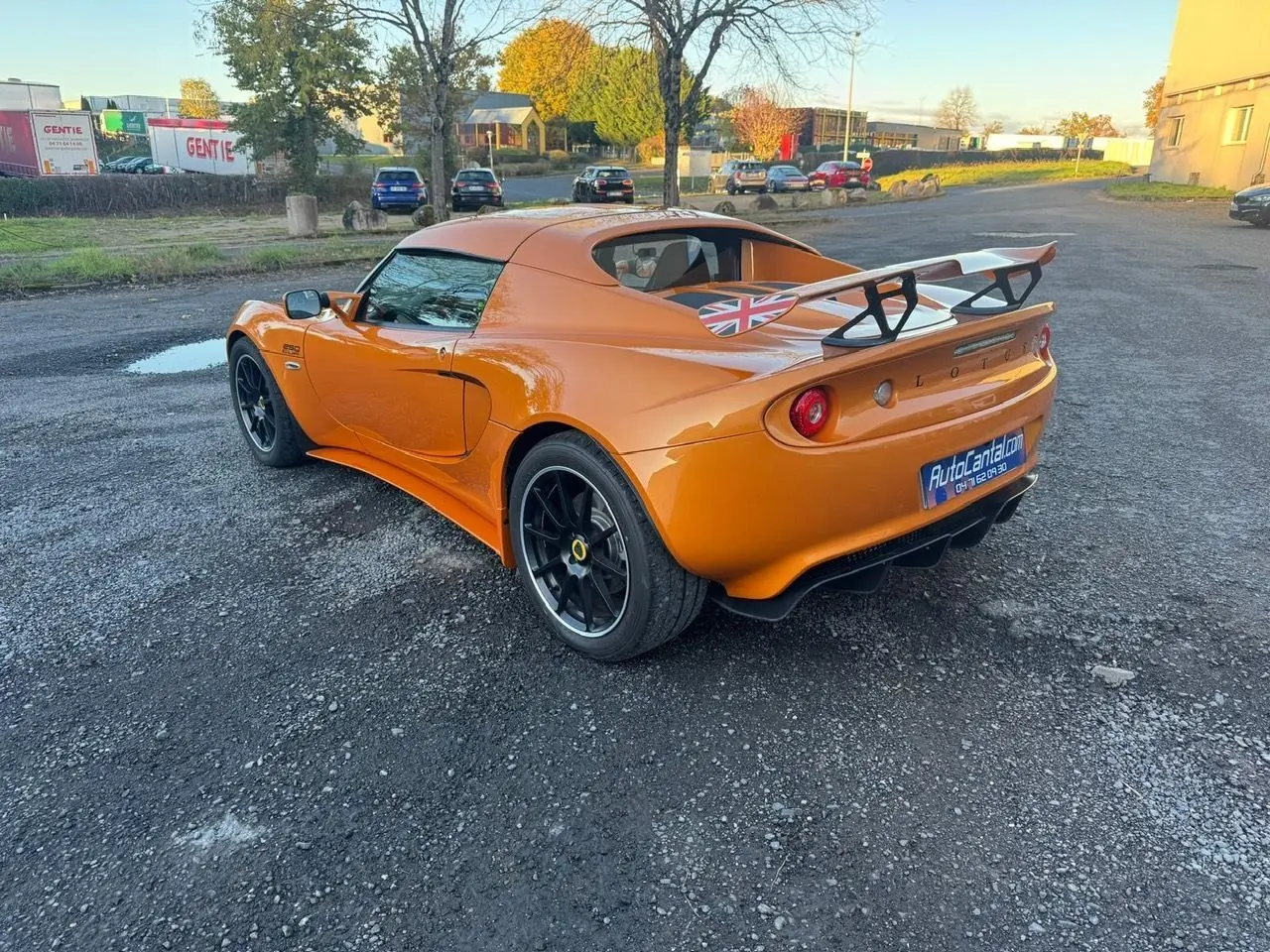 Lotus Elise 3 Cup 250 orange vue 3/4 arrière droit, avec aileron arrière et jantes noires satinées.