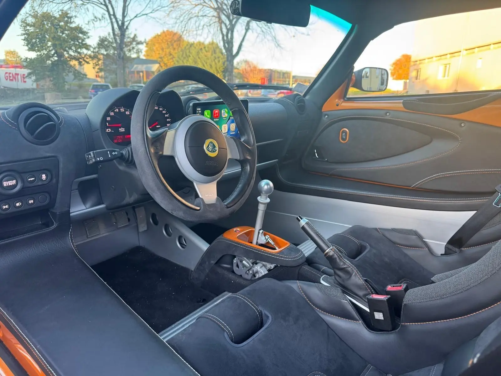 Intérieur côté conducteur de la Lotus Elise 3 Cup 250 orange, volant cuir noir et levier de vitesses aluminium poli.