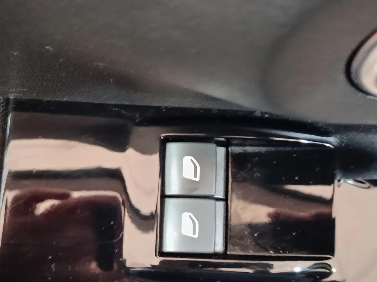 Gros plan sur les boutons de commande des vitres électriques côté conducteur d'une Citroën C3 blanche.