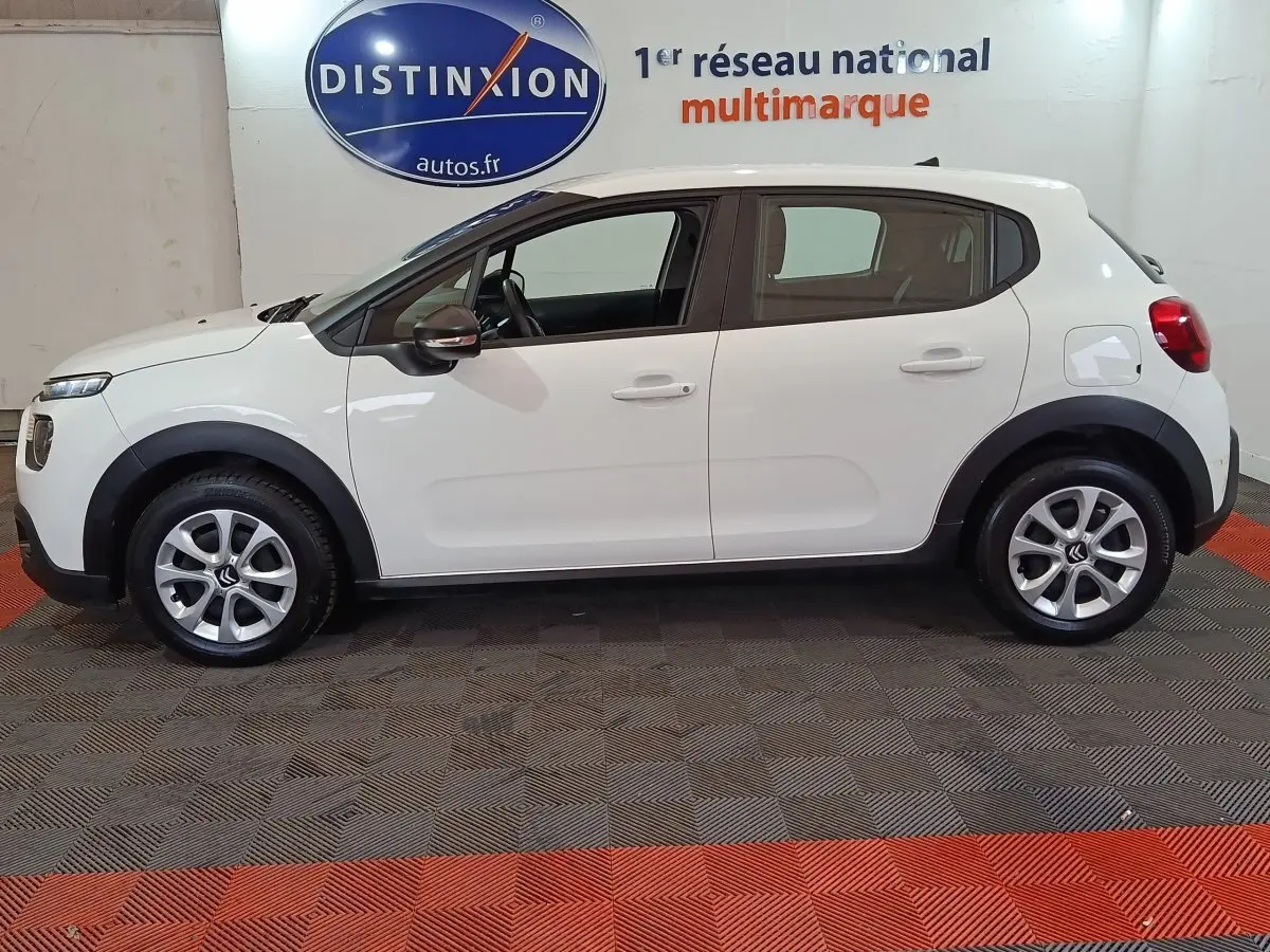 Vue latérale droite d'une Citroën C3 blanche de 2020, avec protections noires autour des roues et rétroviseurs noirs.