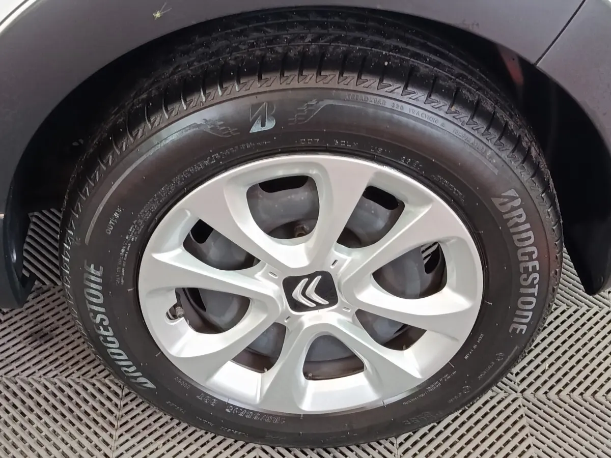 Gros plan sur la roue avant gauche d'une Citroën C3 blanche, avec jante alliage et logo Citroën au centre.
