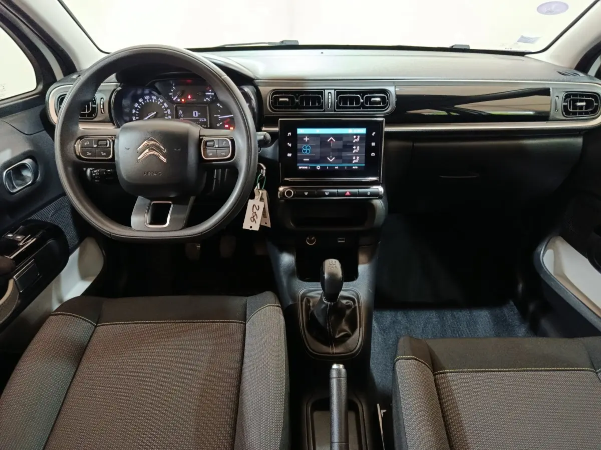 Vue intérieure avant de la Citroën C3 blanche, mettant en valeur le volant multifonctions, la boîte manuelle et l’écran tactile central.
