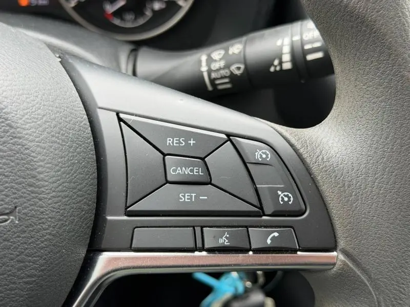 Gros plan sur les commandes de régulateur de vitesse et téléphone au volant du Nissan Juke 2025, intérieur noir.