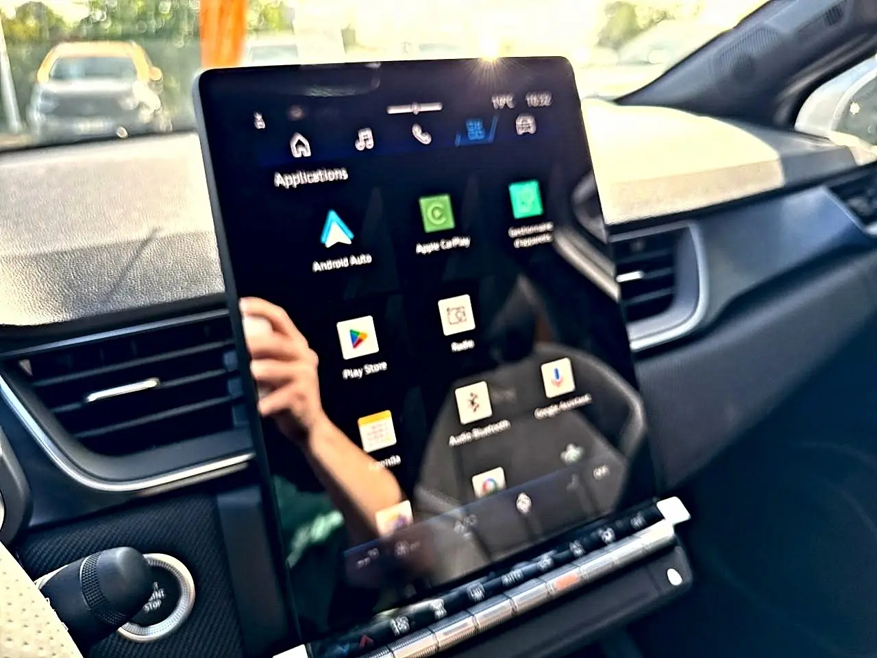 Écran tactile central en plan rapproché dans l’habitacle sombre du Renault Symbioz gris rafale, affichant des applications connectées.