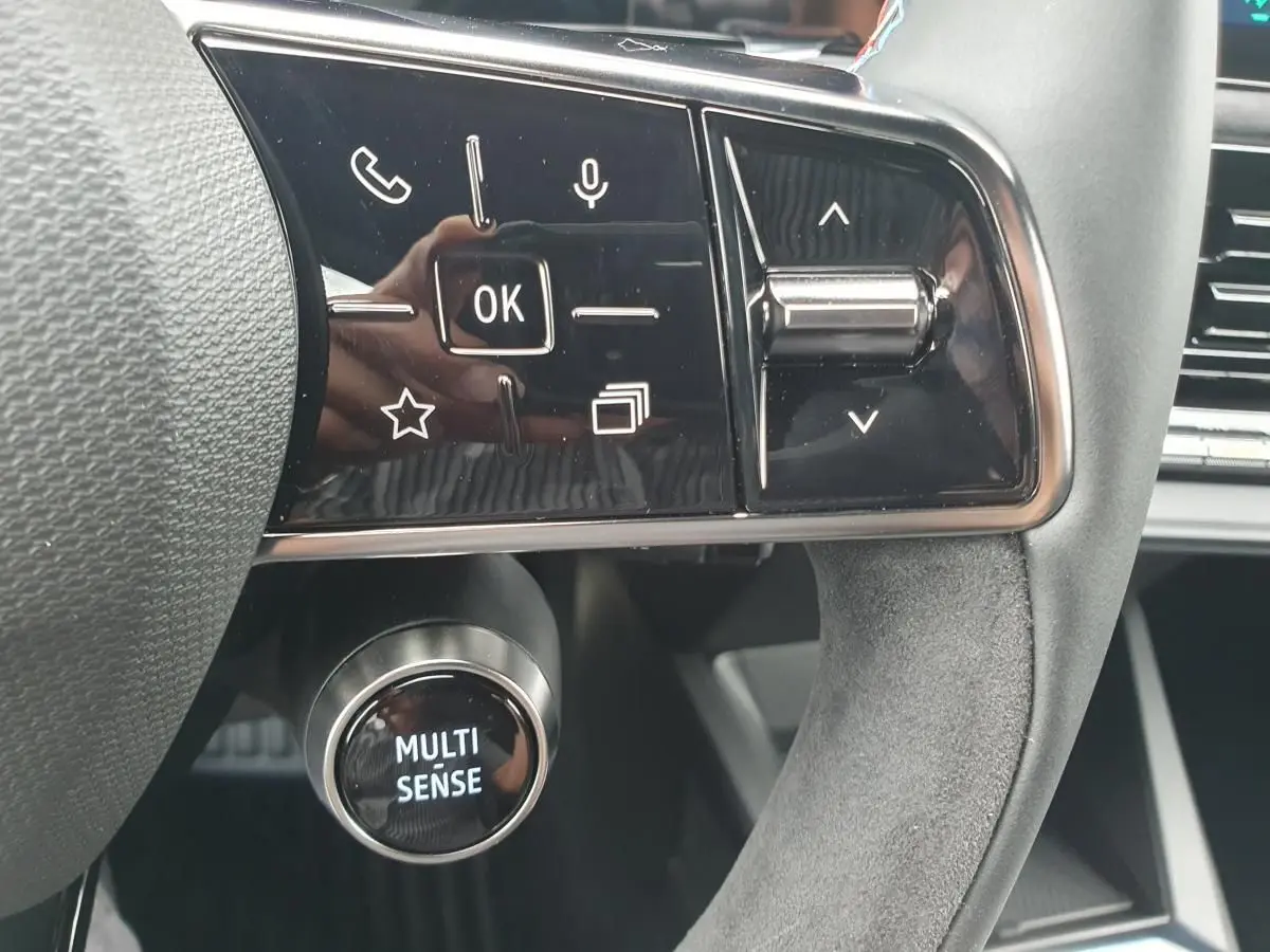 Gros plan sur les commandes multifonctions et le bouton Multi-Sense du volant de la Renault Clio VI hybride.