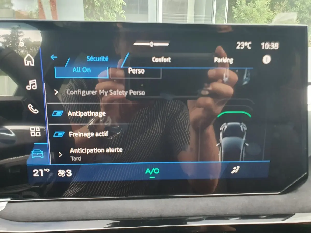 Écran tactile central de la Renault Clio VI hybride, affichant les réglages de sécurité et confort, intérieur noir.