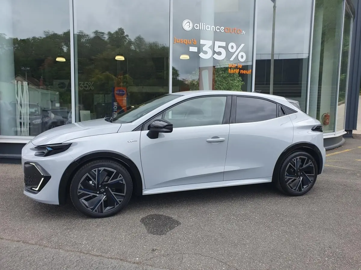 Profil droit de la Renault Clio VI 1.8 E-TECH hybride gris Rafale avec jantes alliage 18 pouces et vitres surteintées.