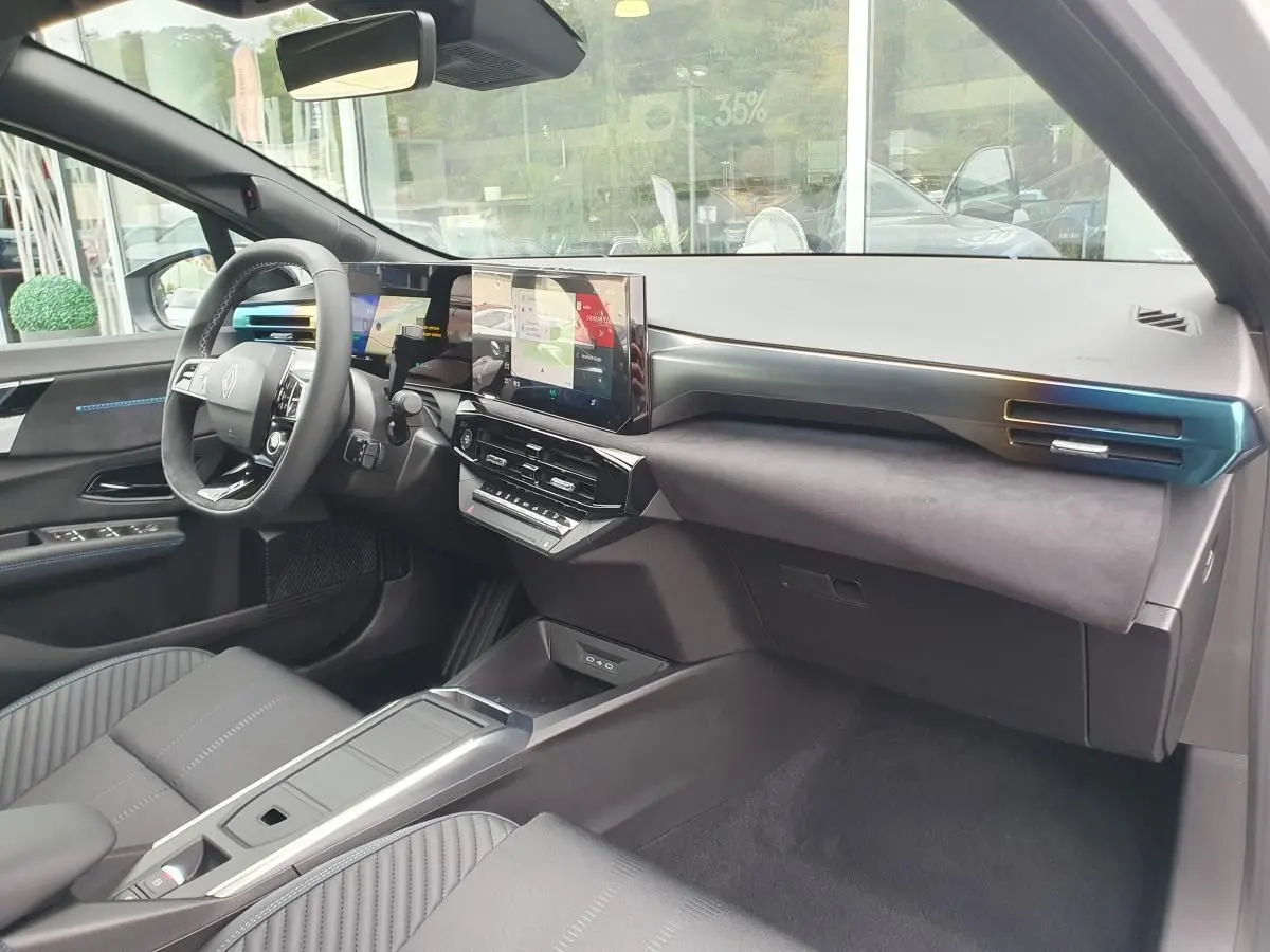 Vue intérieure côté conducteur de la Renault Clio VI hybride 2026, tableau de bord moderne avec écran tactile et volant multifonction.