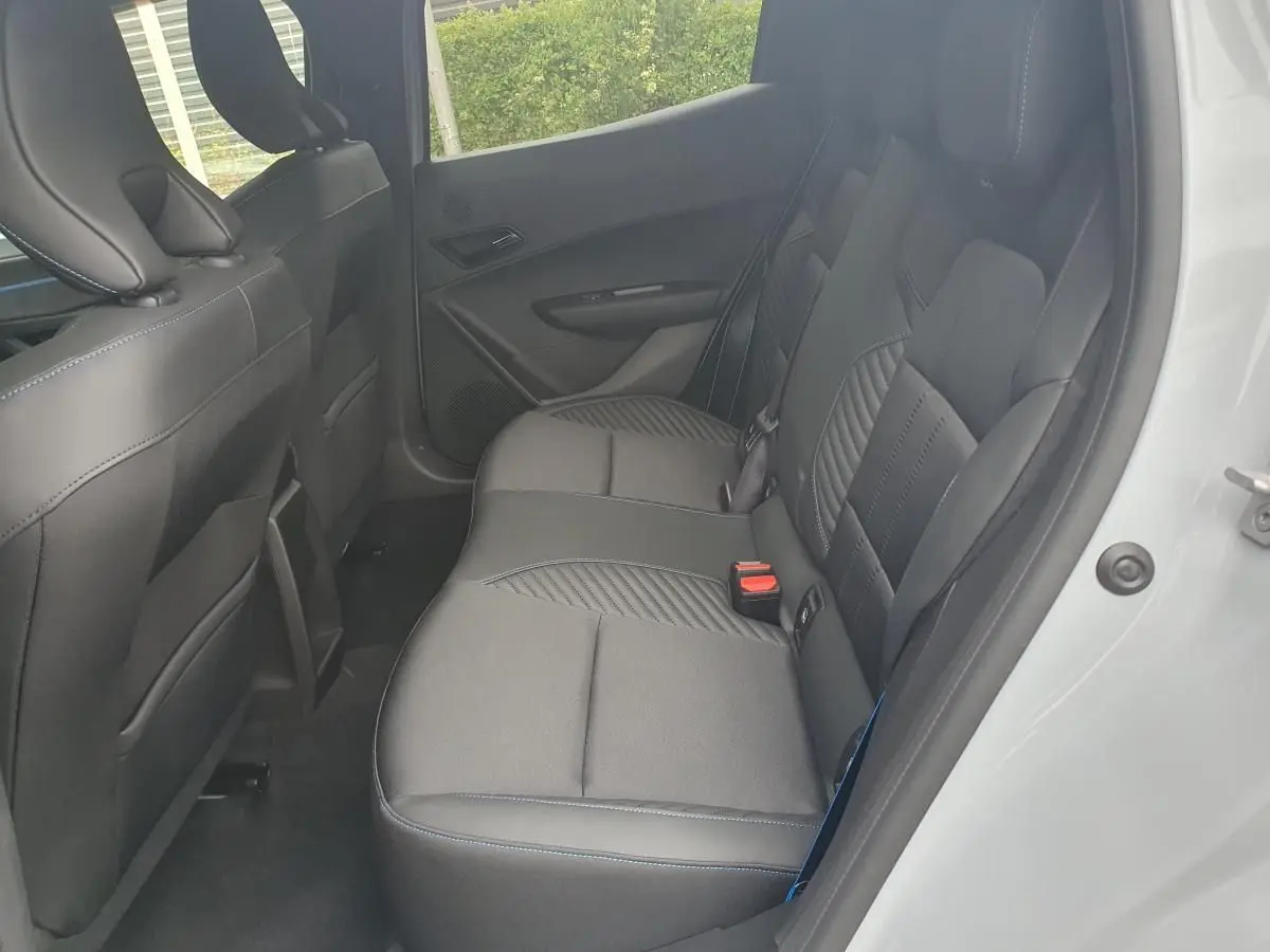 Vue côté droit des sièges arrière en tissu noir avec surpiqûres bleues d’une Renault Clio VI gris Rafale, porte ouverte.