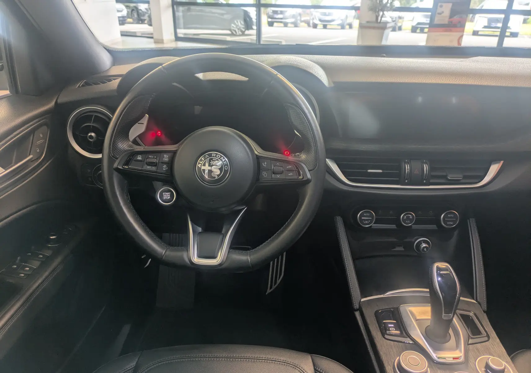 Intérieur noir de l'Alfa Romeo Stelvio 2023, vue frontale du poste de conduite avec volant et console centrale.