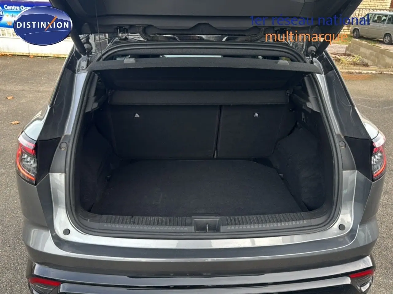 Coffre ouvert en vue arrière d'un Renault Austral gris schiste avec toit noir, montrant l'espace de chargement vide.