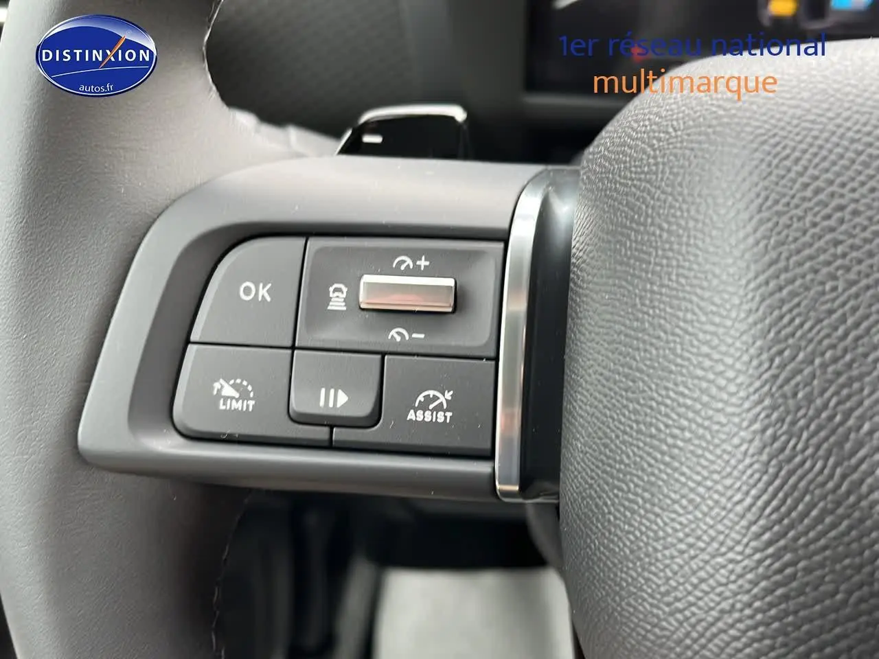 Gros plan sur les commandes au volant cuir noir d'une Citroën C4 noire métal 2025, côté gauche, avec régulateur adaptatif.