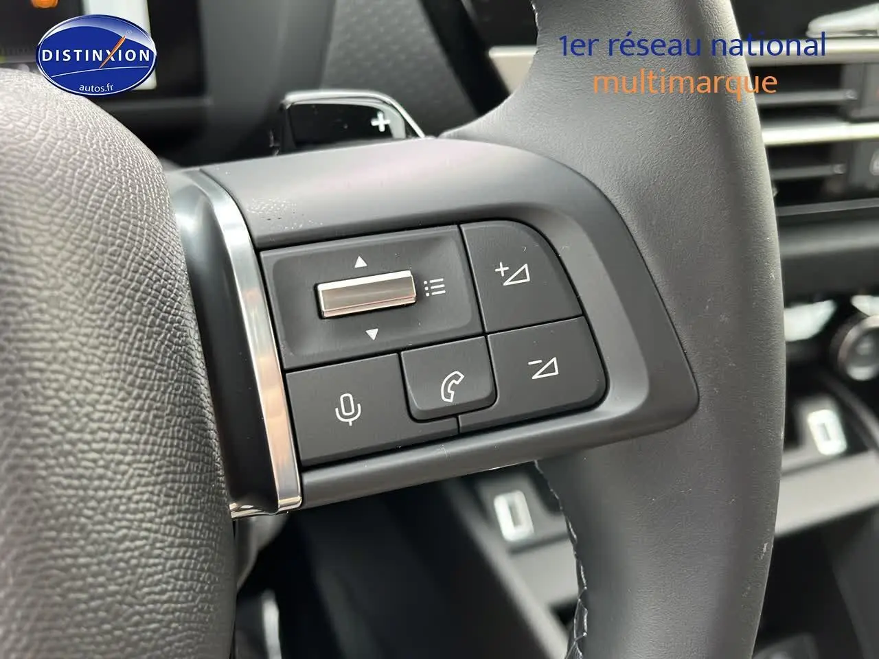 Gros plan sur les commandes gauche du volant cuir noir de la Citroën C4 1.2 hybride 2025, avec boutons multifonctions.