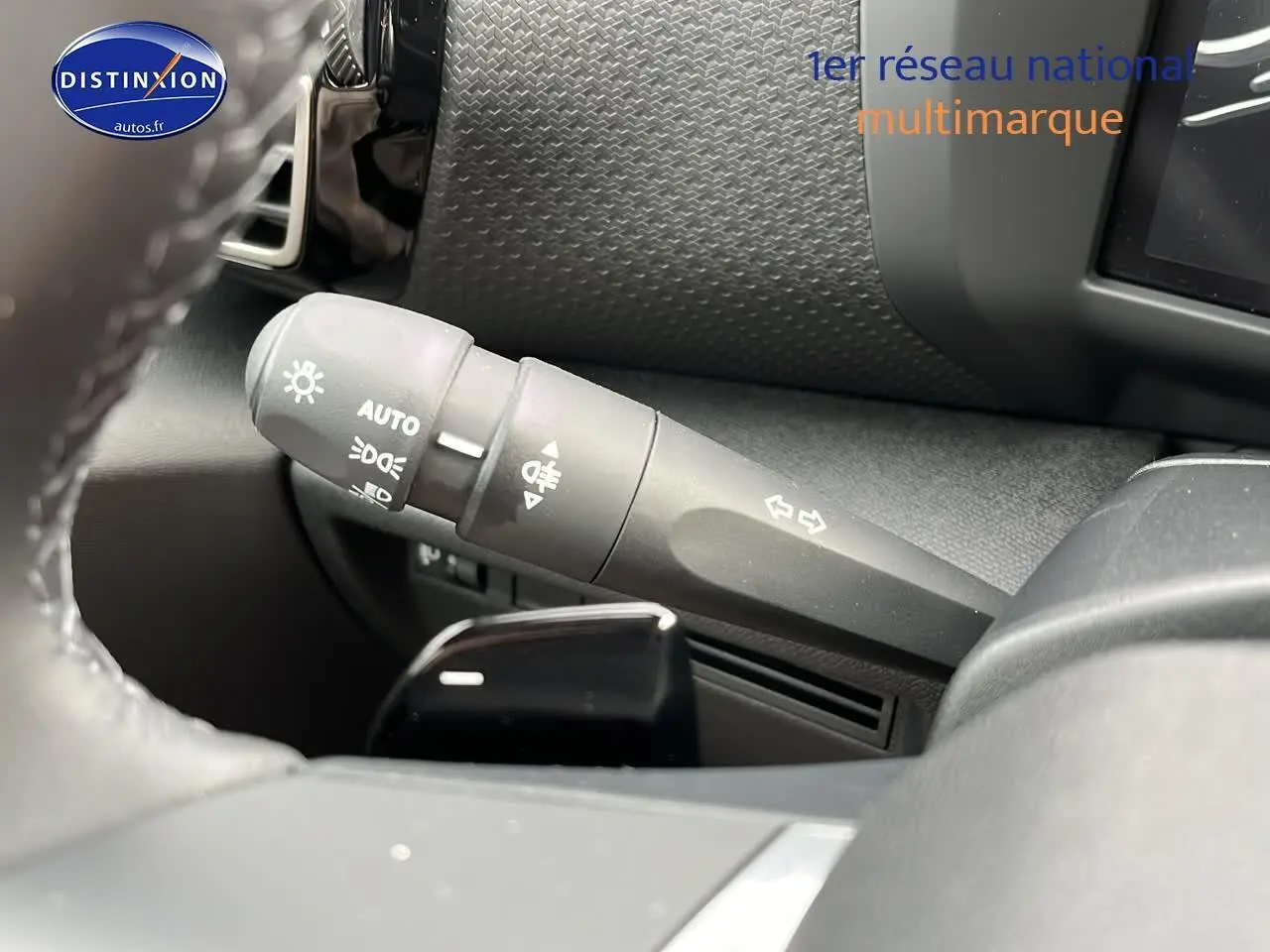 Gros plan sur la commande des feux et clignotants à gauche du volant cuir dans l’habitacle noir du Citroën C4 2025.