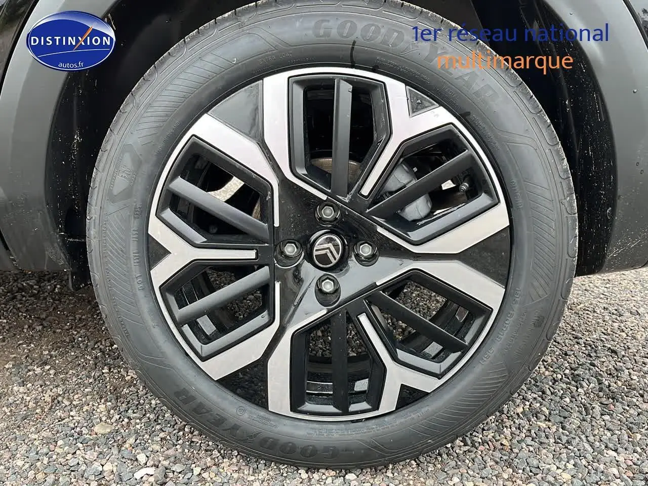 Vue latérale côté gauche d'une Citroën C4 noire métal avec jantes alliage 18 pouces sur sol gravillonné.