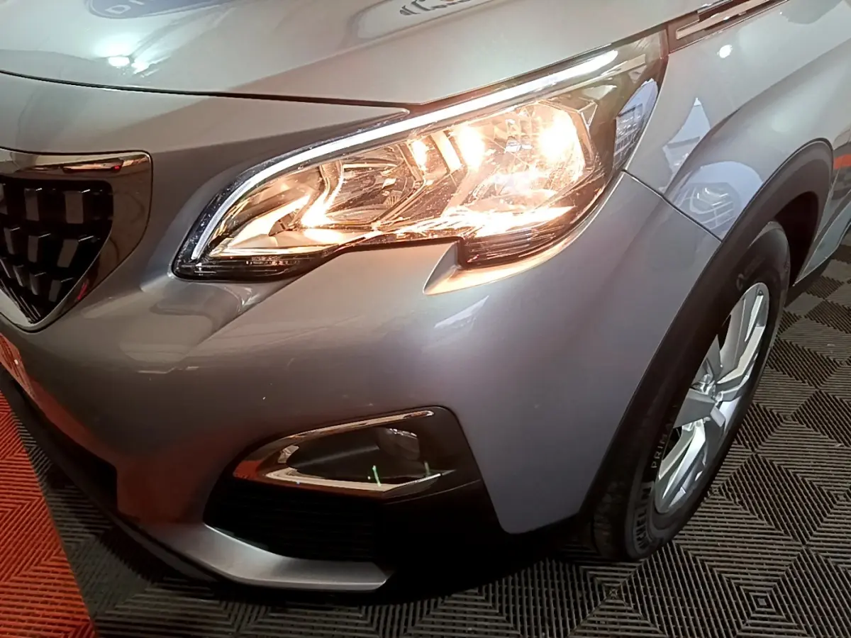 Gros plan sur l'avant droit gris clair du Peugeot 3008 avec phare allumé et jante visible.