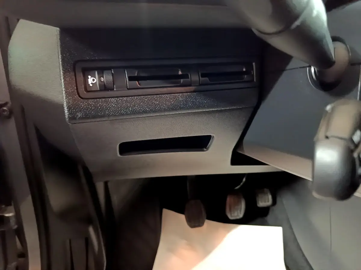 Vue intérieure en gros plan du tableau de bord côté gauche avec commandes d'éclairage et pédales d'une Peugeot 3008 gris clair.