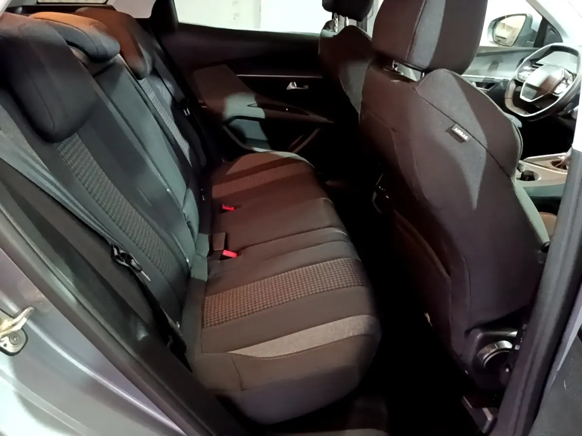 Vue intérieure côté gauche des sièges arrière noirs du Peugeot 3008 gris clair, avec partie avant et volant visibles.