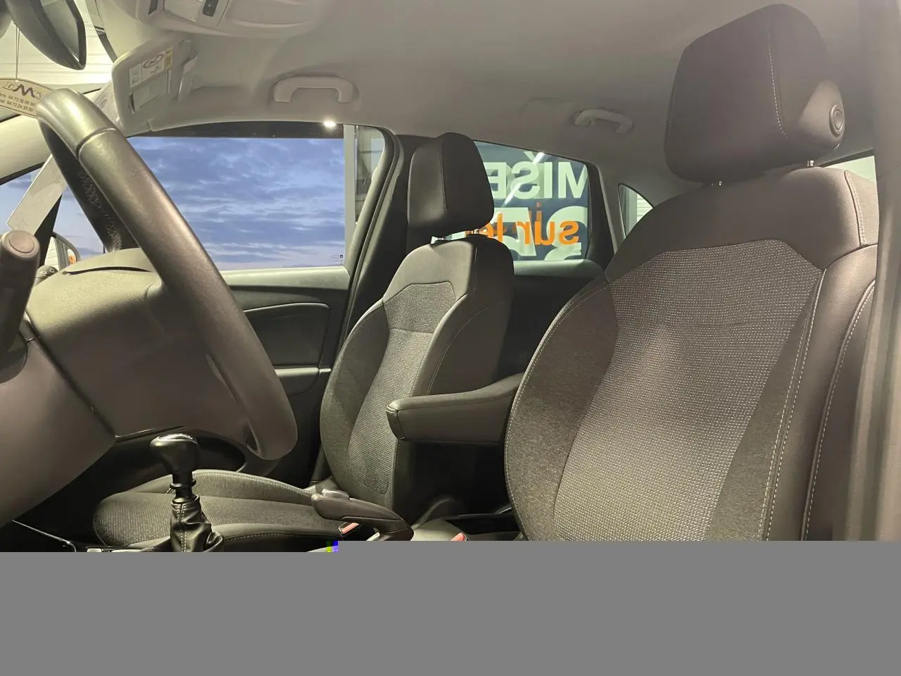 Vue intérieure côté conducteur de l’Opel Crossland 2024, sièges tissu noir avec accoudoir central et volant cuir.