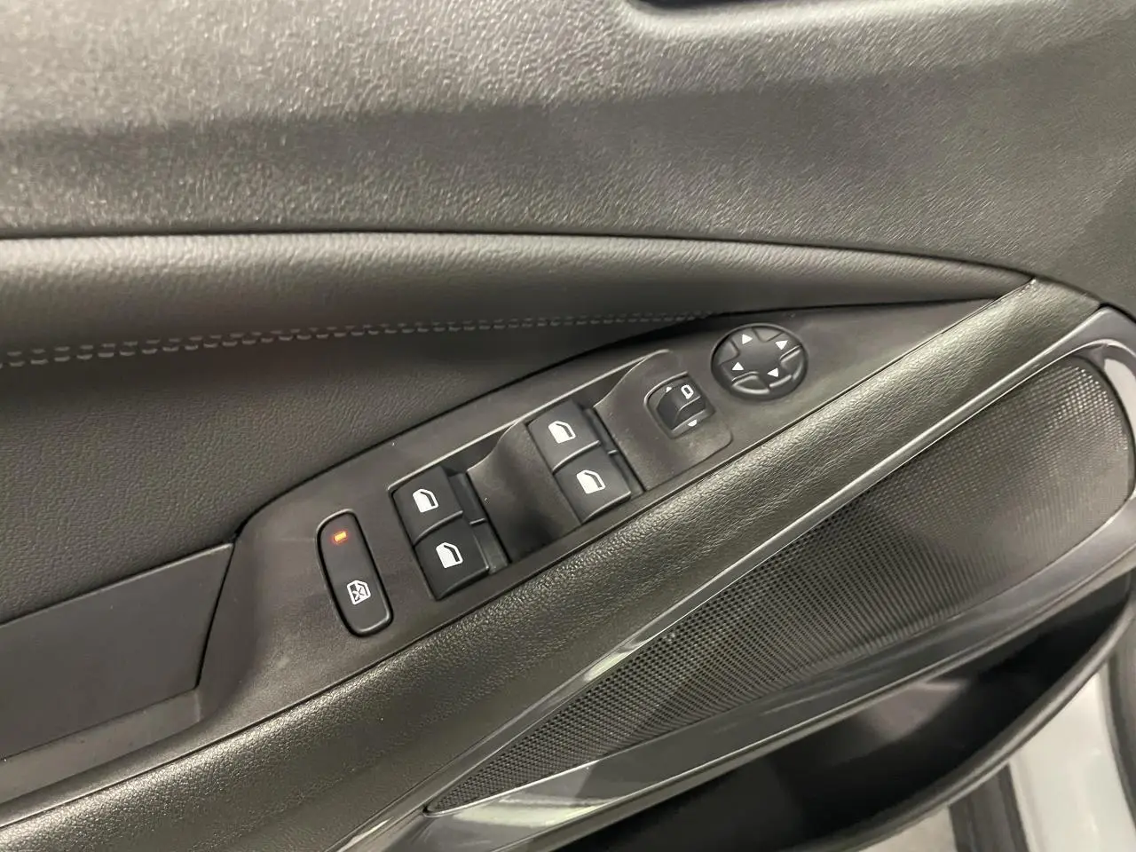 Détail des commandes de lève-vitres et rétroviseurs sur la porte avant gauche d’un Opel Crossland gris clair.