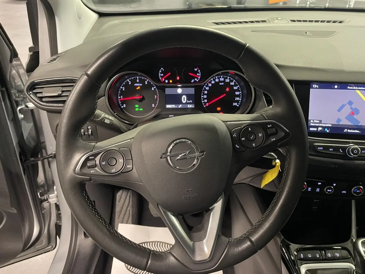 Vue intérieure centrée sur le volant cuir noir d’Opel Crossland gris clair avec tableau de bord et écran tactile visible.