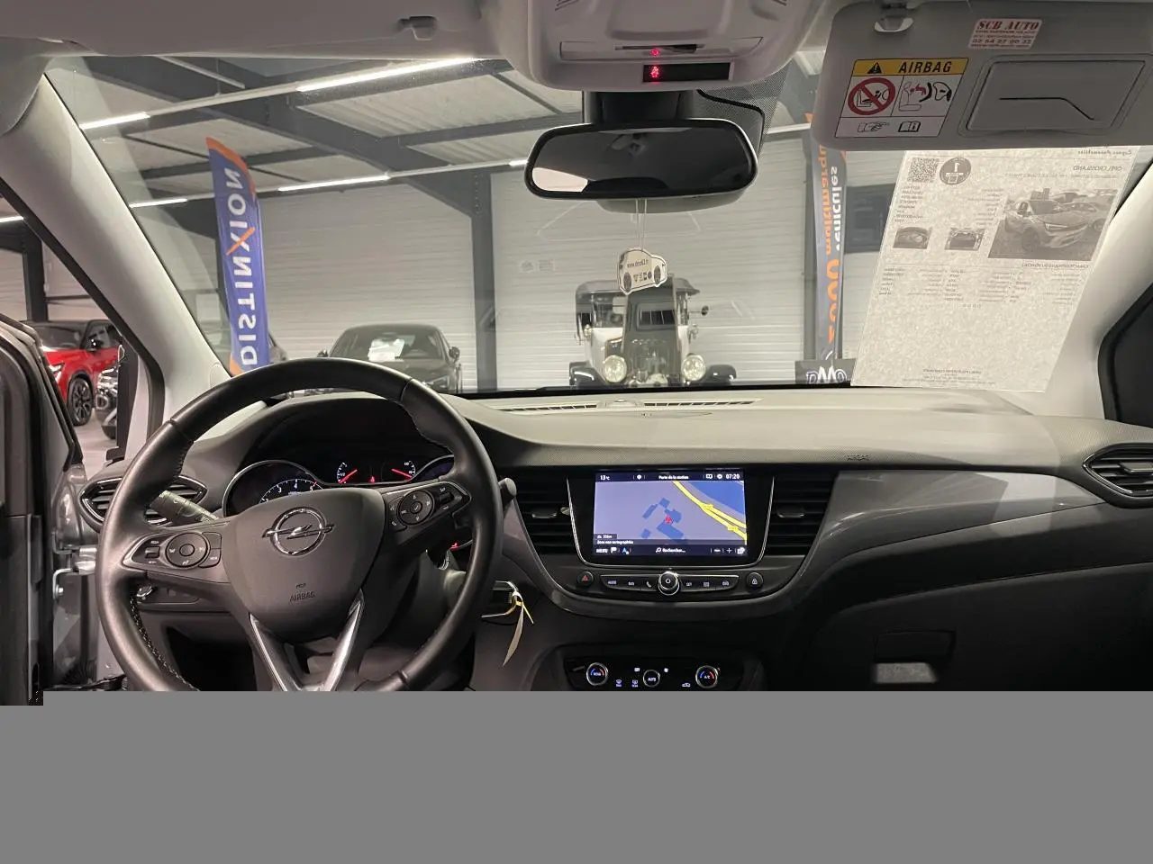 Vue intérieure avant de l’Opel Crossland gris clair 2024, volant cuir, écran tactile 8 pouces avec navigation affichée.