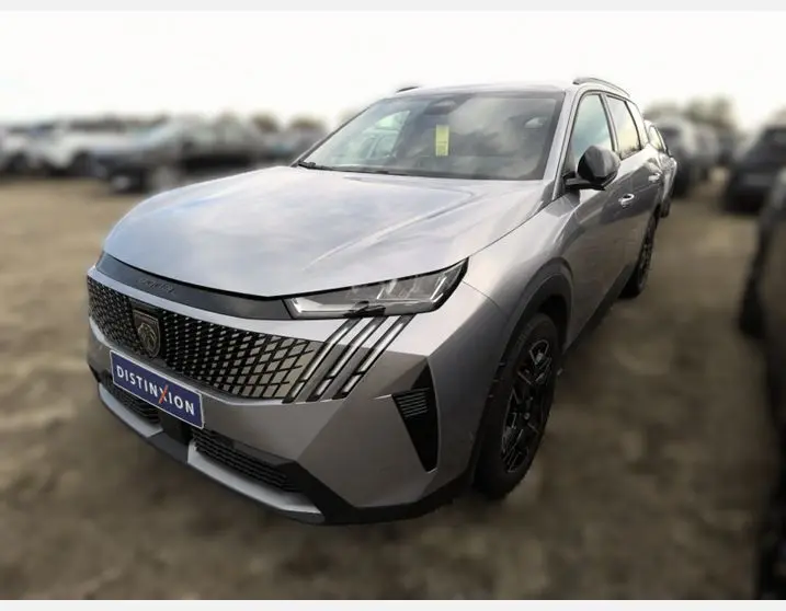 Vue 3/4 avant droite d'un Peugeot 5008 gris Artense avec calandre distinctive et phares LED fins.