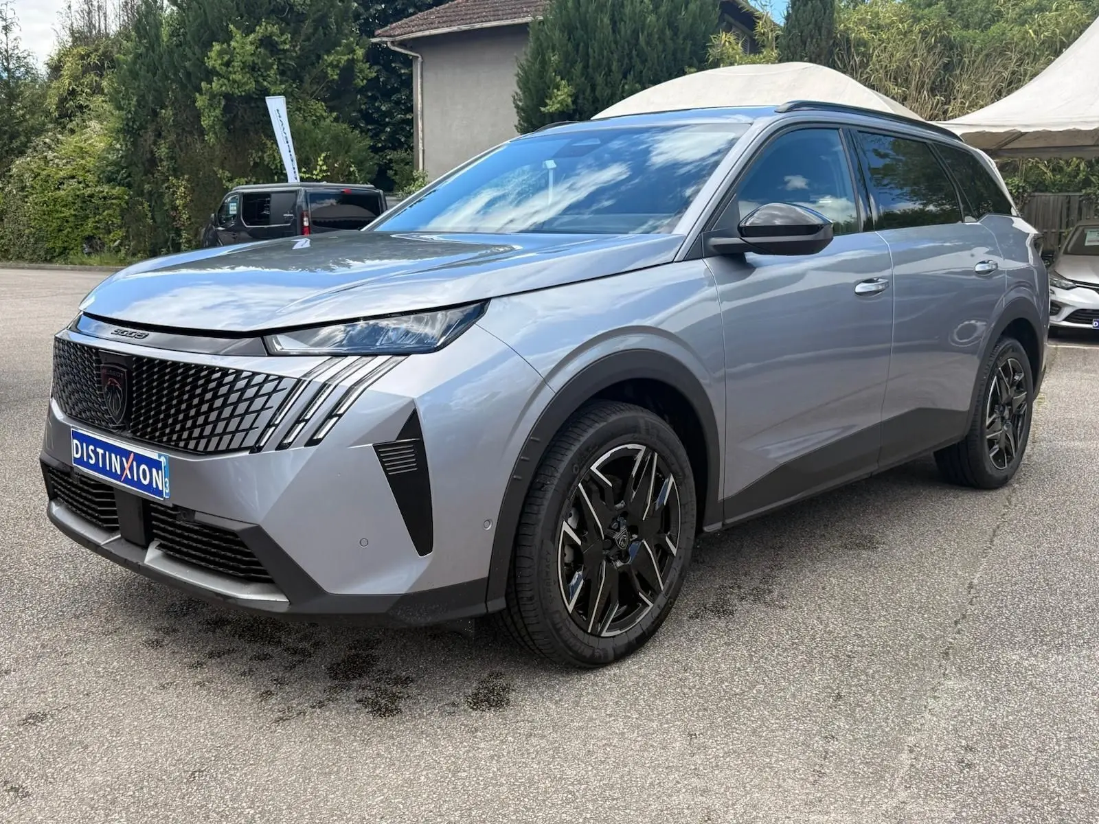 Peugeot 5008 Hybrid gris Artense vue 3/4 avant droit, avec calandre noire et jantes alliage noires distinctives.