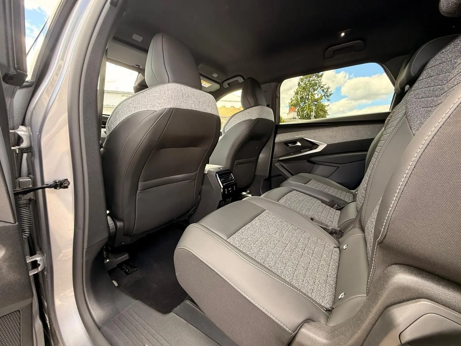Vue intérieure côté gauche des sièges arrière du Peugeot 5008 Hybrid 145 finition Allure, avec sellerie bi-matière grise et noire.