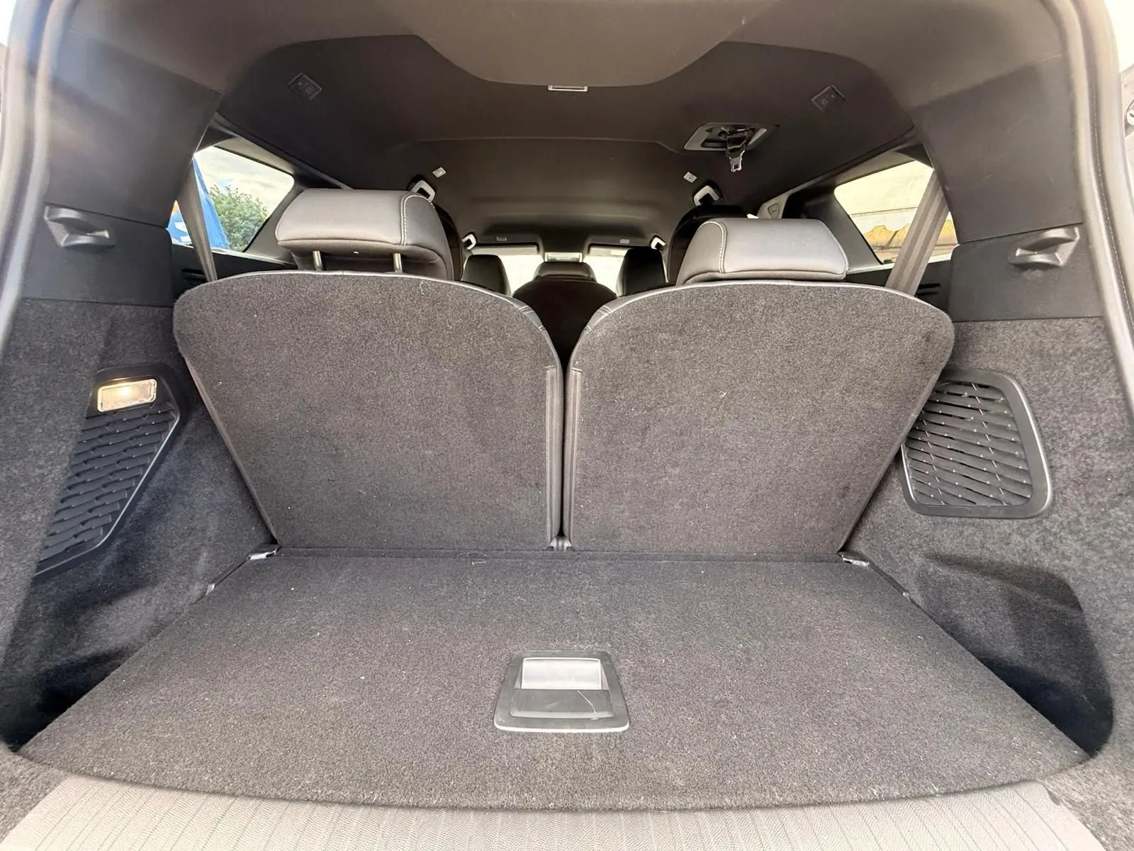 Vue intérieure du coffre du Peugeot 5008 Hybrid 145 gris Artense, montrant les sièges arrière relevés et l'espace de chargement.