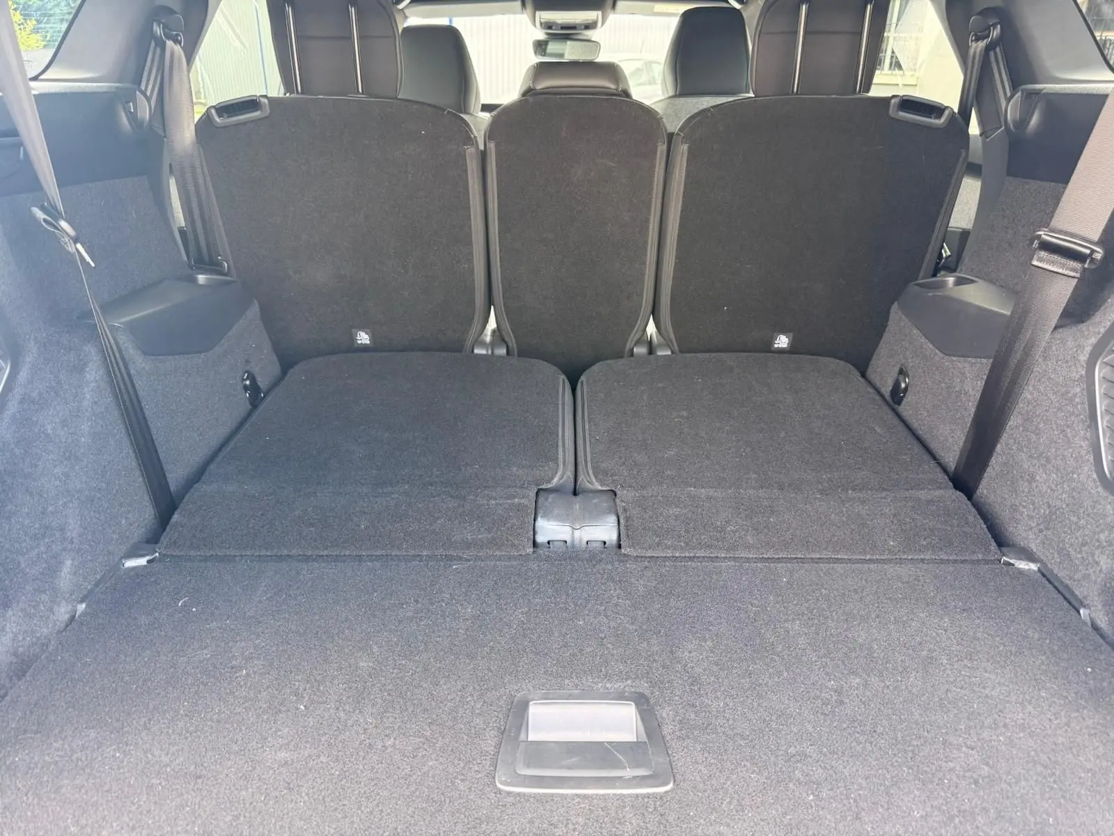 Vue arrière du coffre du Peugeot 5008 Hybrid 145 gris Artense avec sièges rabattus et espace de chargement plat.
