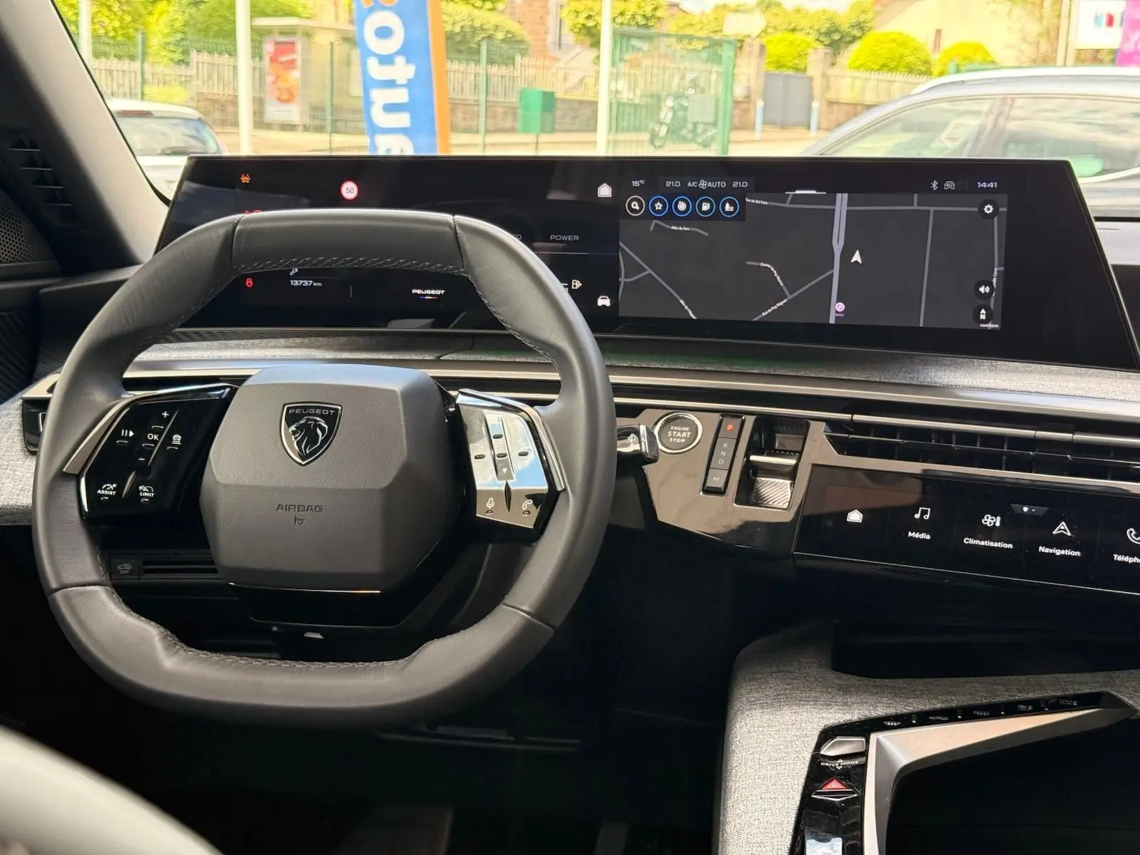 Vue intérieure centrée sur le volant compact et le tableau de bord numérique large du Peugeot 5008 Hybrid gris Artense.