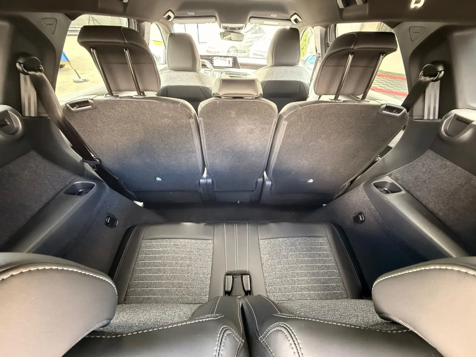 Vue intérieure du coffre du Peugeot 5008 Hybrid 145 gris Artense, sièges arrière relevés et banquette en tissu et cuir.