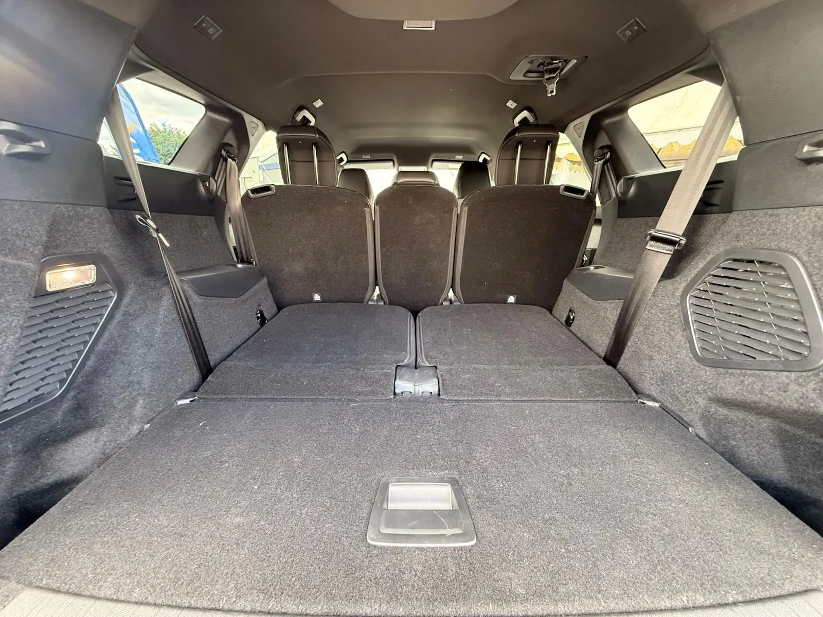 Vue intérieure arrière du coffre du Peugeot 5008 hybride 2025, sièges rabattus et habillage noir.