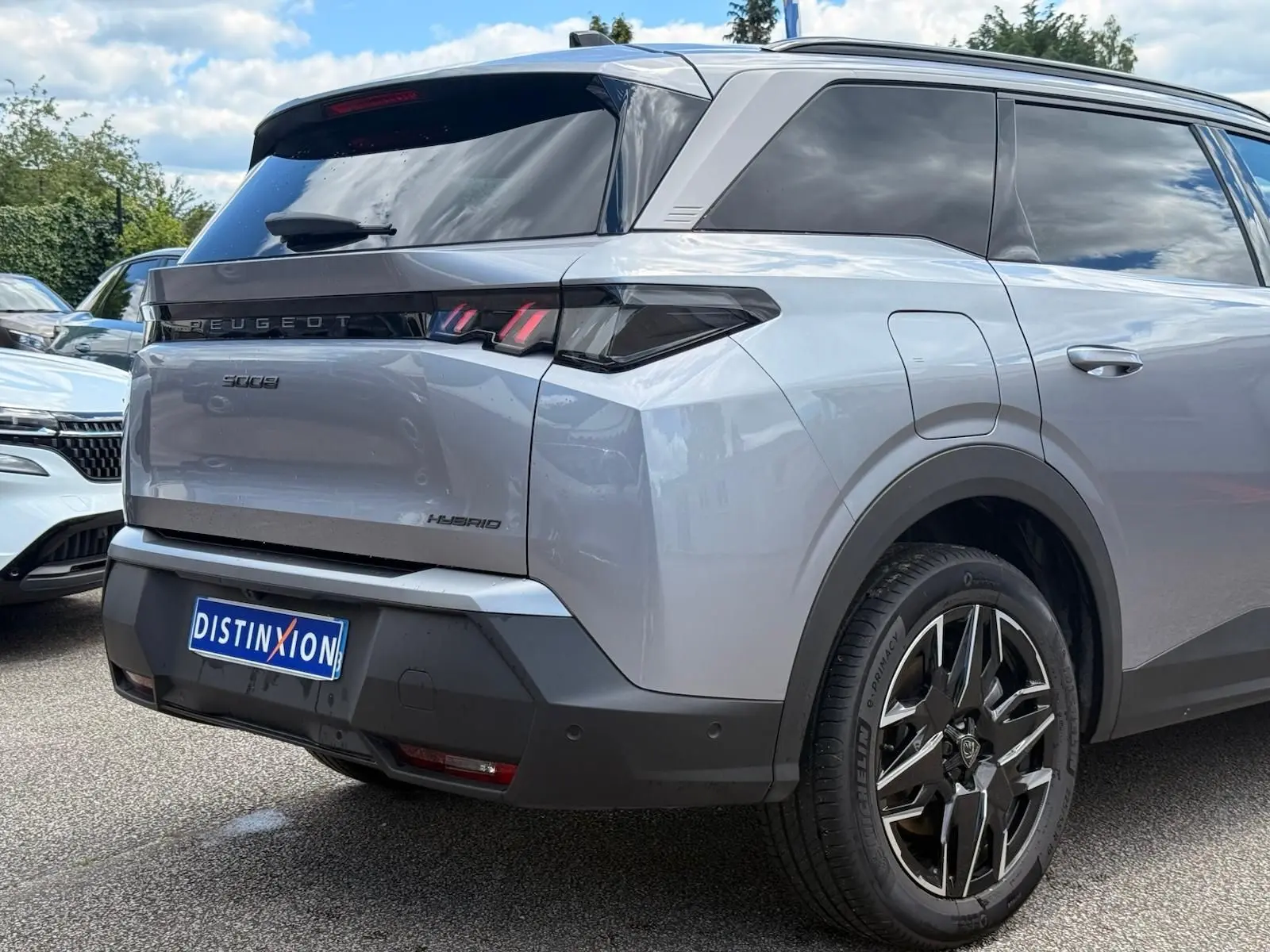 Vue 3/4 arrière droite du Peugeot 5008 Hybrid gris Artense avec feux arrière LED et jantes alliage distinctives.