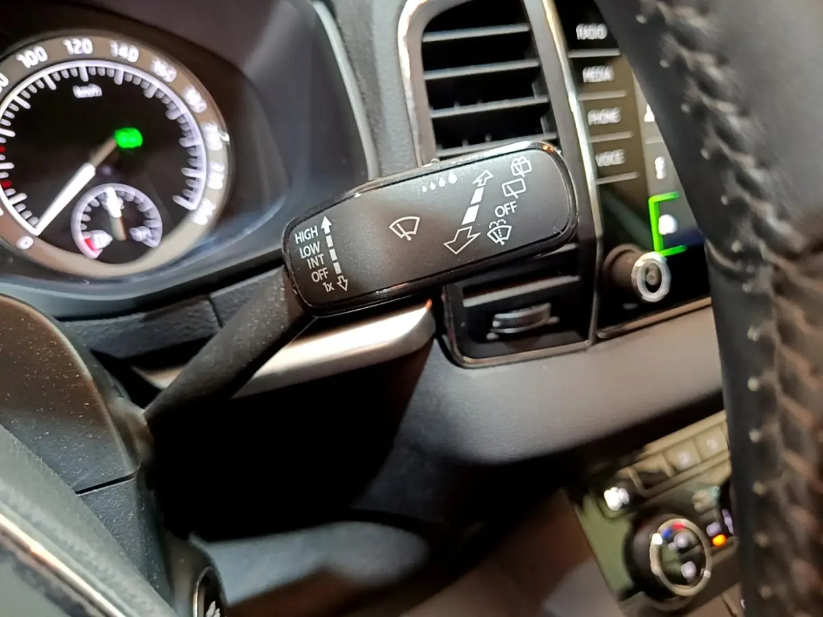 Gros plan sur la commande d’essuie-glace à gauche du volant cuir dans le tableau de bord noir du Skoda Karoq gris clair.
