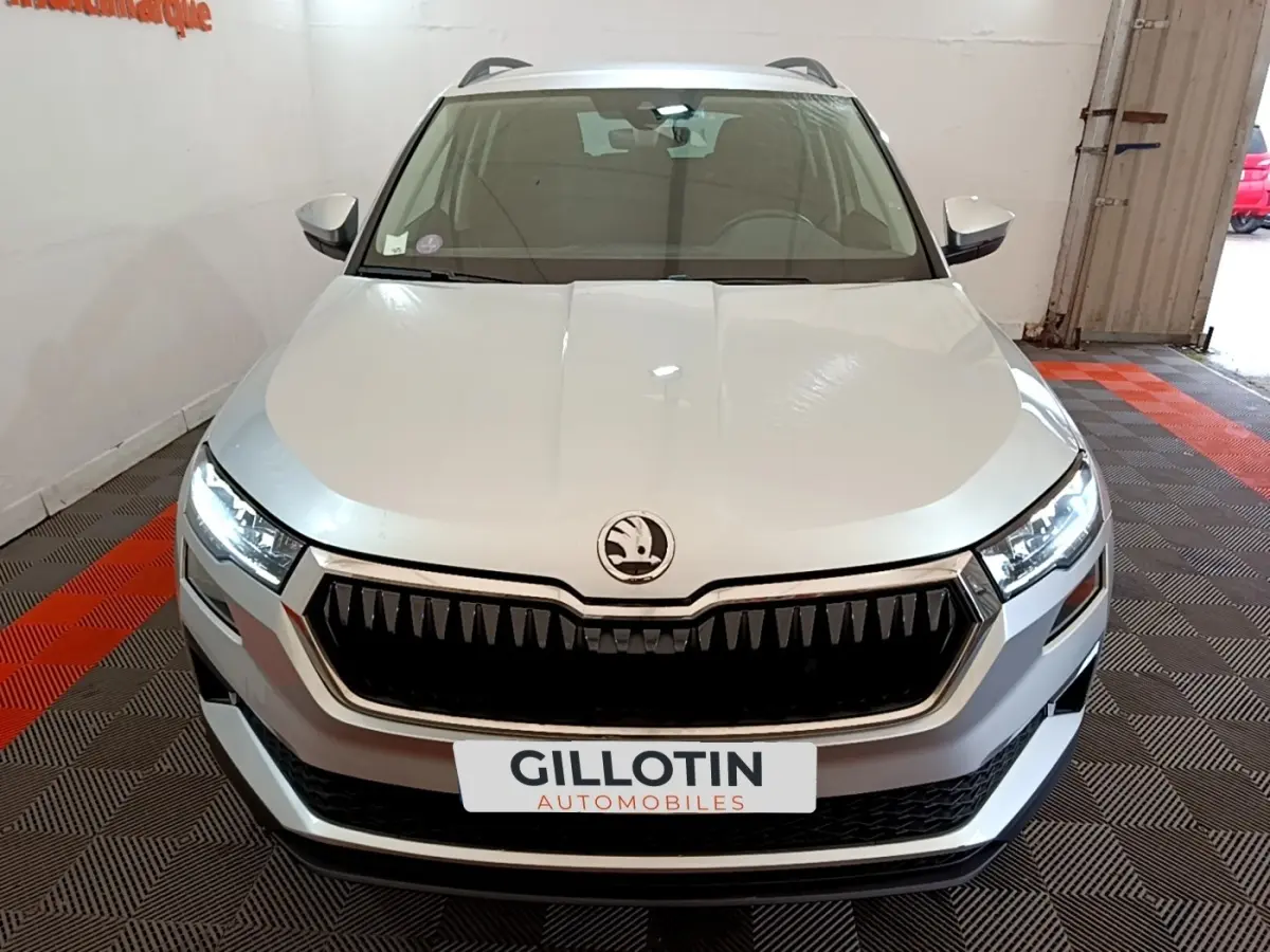 Vue frontale d'un Skoda Karoq gris clair avec calandre noire distinctive et phares LED allumés.