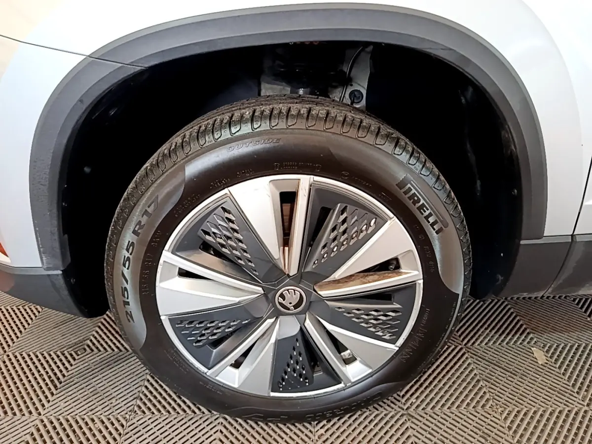 Gros plan sur la roue avant gauche d’un Skoda Karoq gris clair avec jante alliage au design moderne.