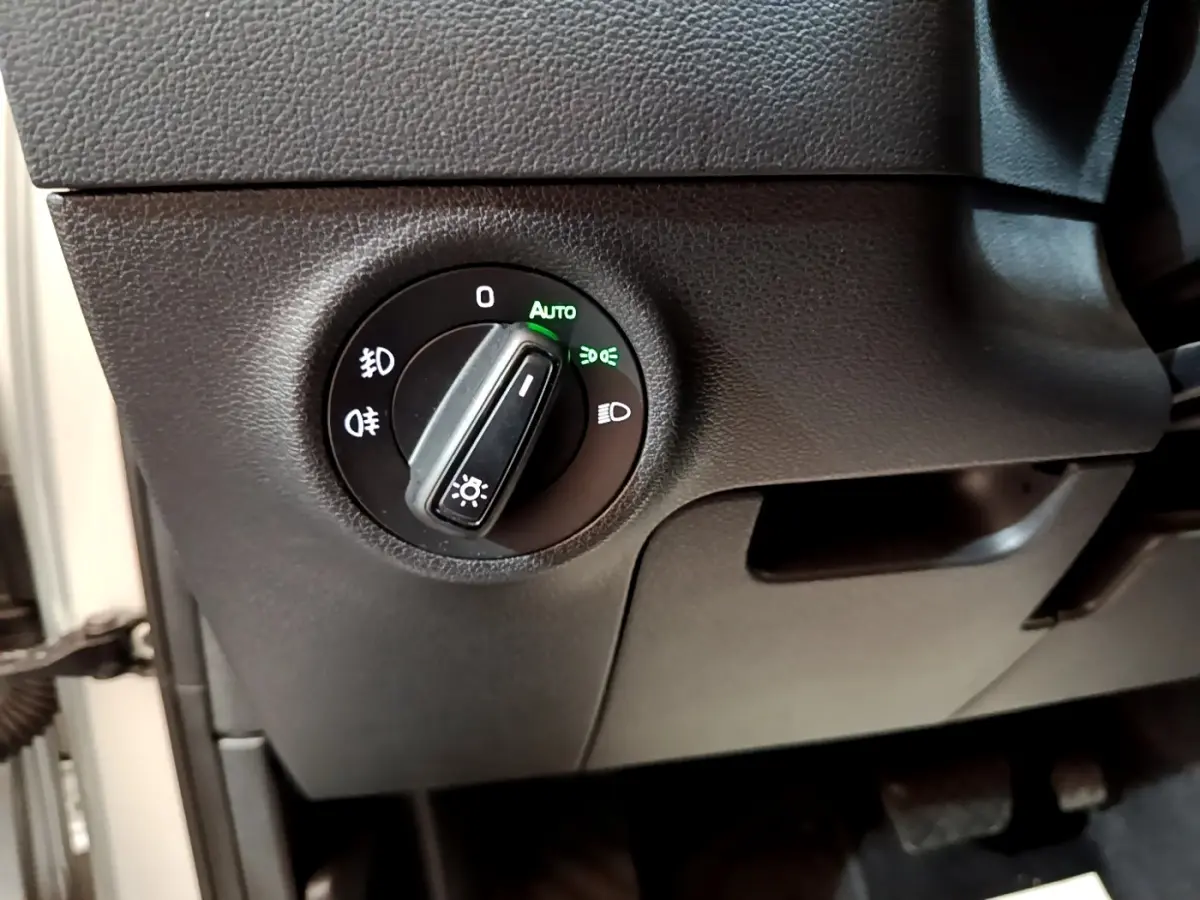 Gros plan sur le bouton de commande des phares du Skoda Karoq 2022, intérieur noir avec éclairage vert "Auto" activé.