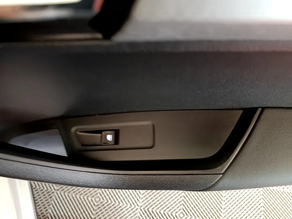 Détail de la commande de verrouillage des portes côté conducteur du Skoda Karoq gris clair, intérieur noir.
