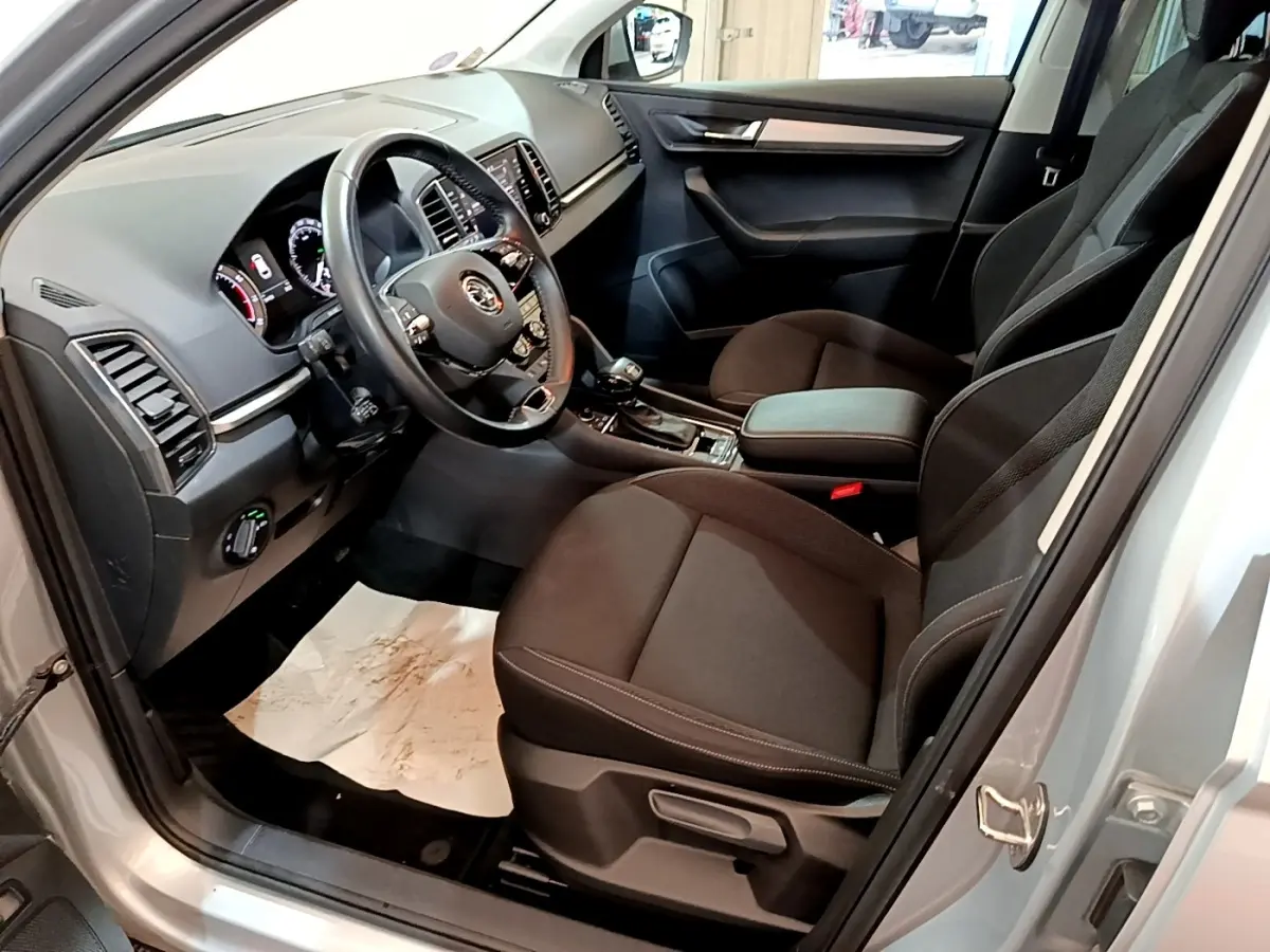 Vue intérieure côté conducteur du Skoda Karoq gris clair 2022, montrant le tableau de bord et les sièges noirs.