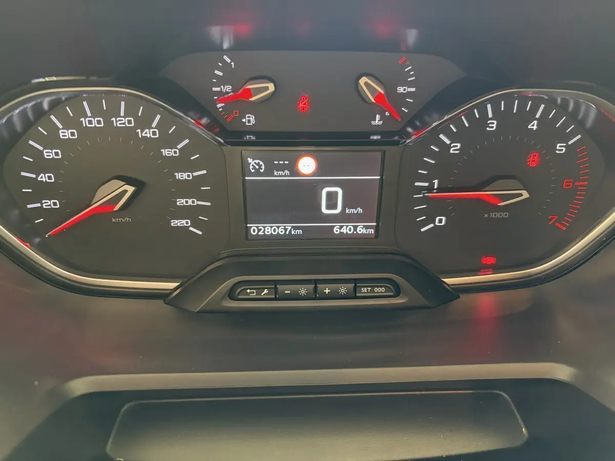 Vue rapprochée du tableau de bord numérique du Peugeot Rifter PureTech 110 blanc, affichant la vitesse à 0 km/h.