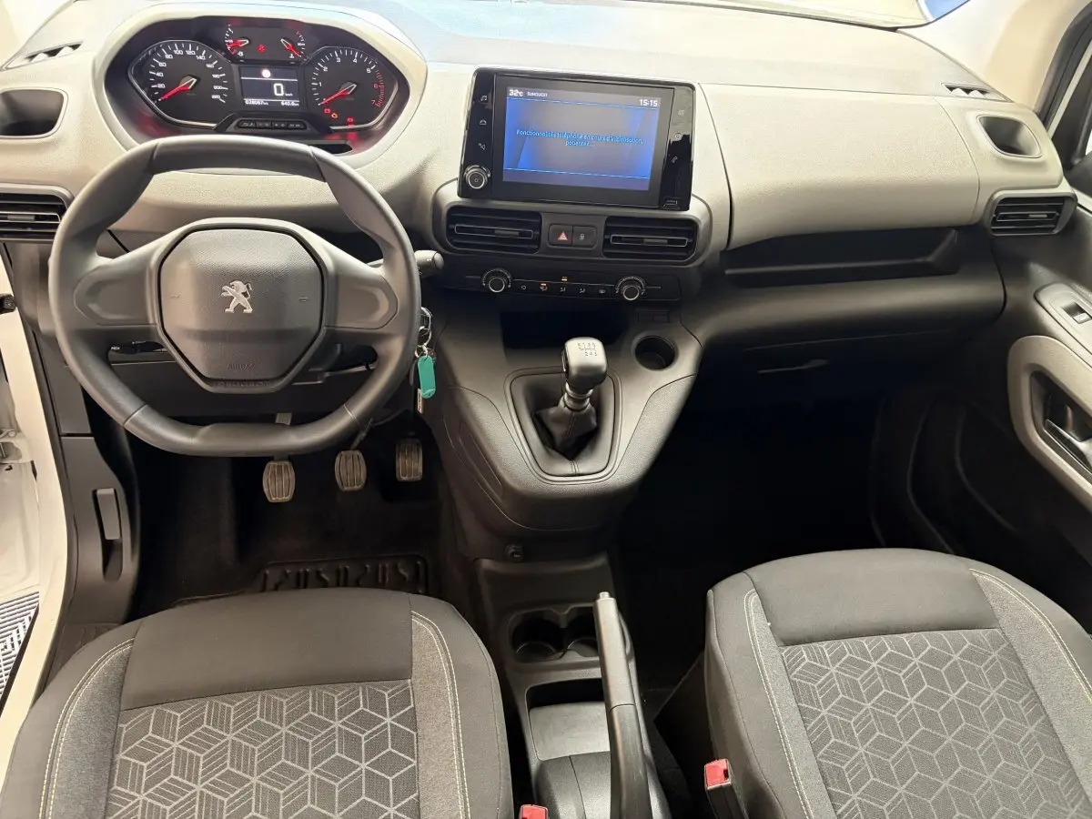 Vue intérieure avant du Peugeot Rifter blanc 2021, volant compact, tableau de bord numérique et levier de vitesses manuel.
