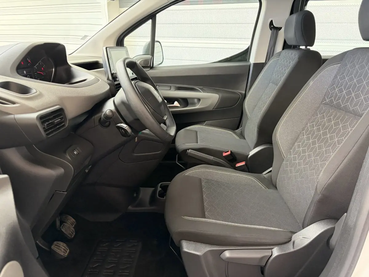 Vue intérieure côté conducteur du Peugeot Rifter 2021, sièges tissu gris et volant multifonctions noir.